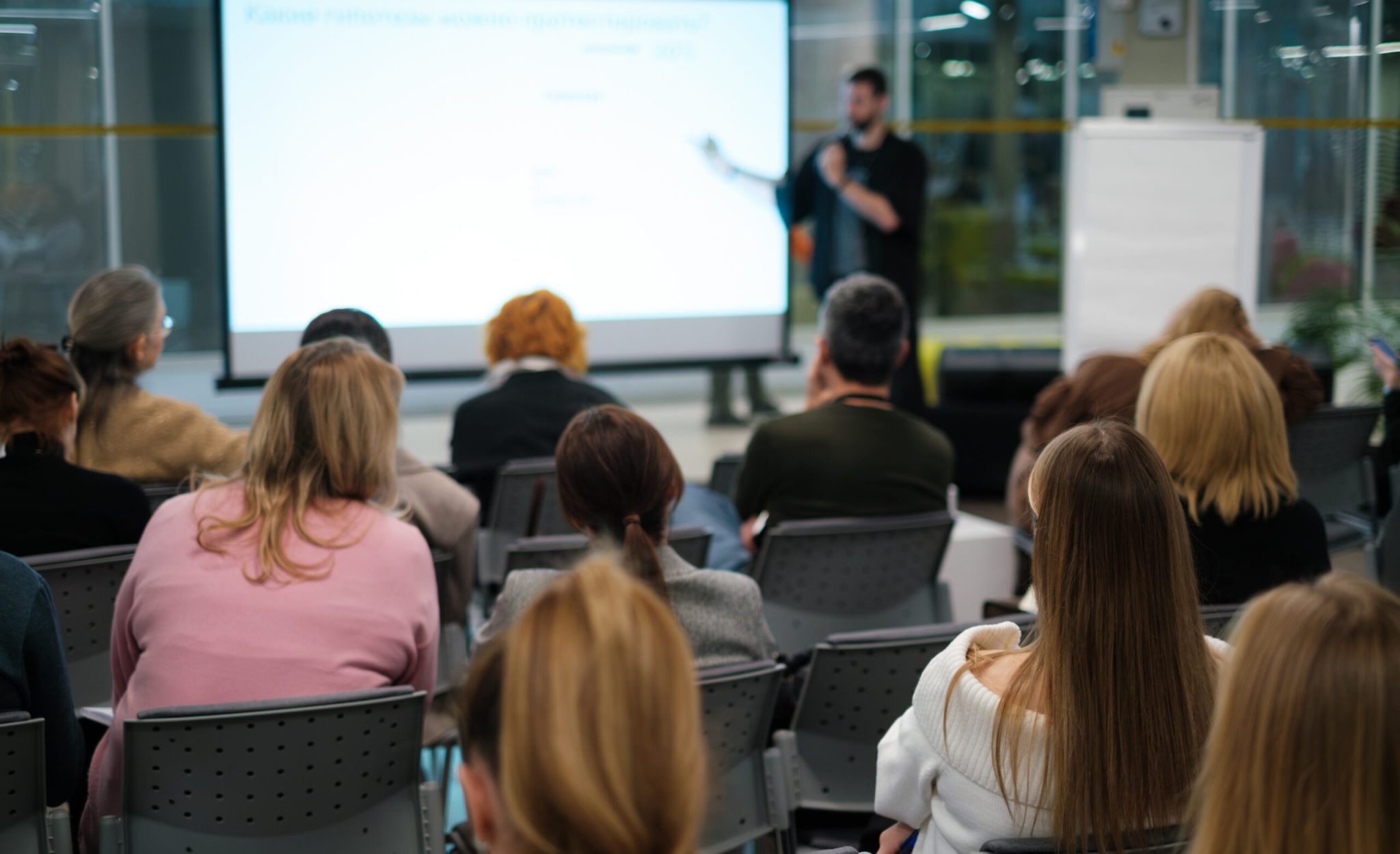 Business presentation with diverse audience in office setting, focusing on learning and networking within a corporate environment.